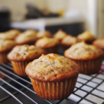 "Freshly baked banana bread mini muffins on a plate, golden brown and delicious."